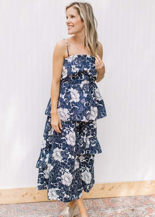 Model wearing a navy set with white flowers, top has spaghetti straps and skirt is midi length.