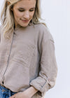 Close up of 3/4 button on a long sleeve taupe button up with a raw hemline and gauze material. 