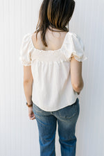 Back view of Model wearing a cream top with a smocked yolk, bubble short sleeves and a square neck.