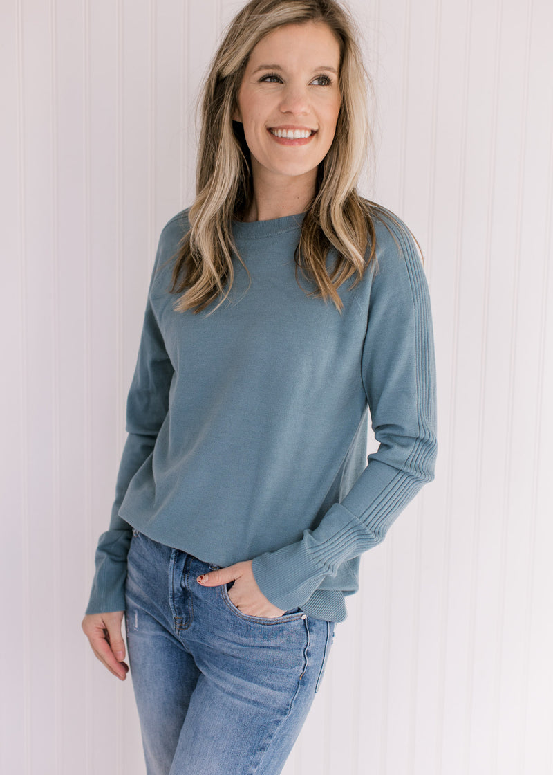 Model wearing an ultra soft, light blue sweater with a crew neckline and long sleeves.