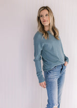 Model wearing jeans with an ultra soft, light blue sweater with a crew neckline and long sleeves.
