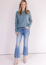 Model wearing jeans and booties with a light blue sweater with a crew neckline and long sleeves.