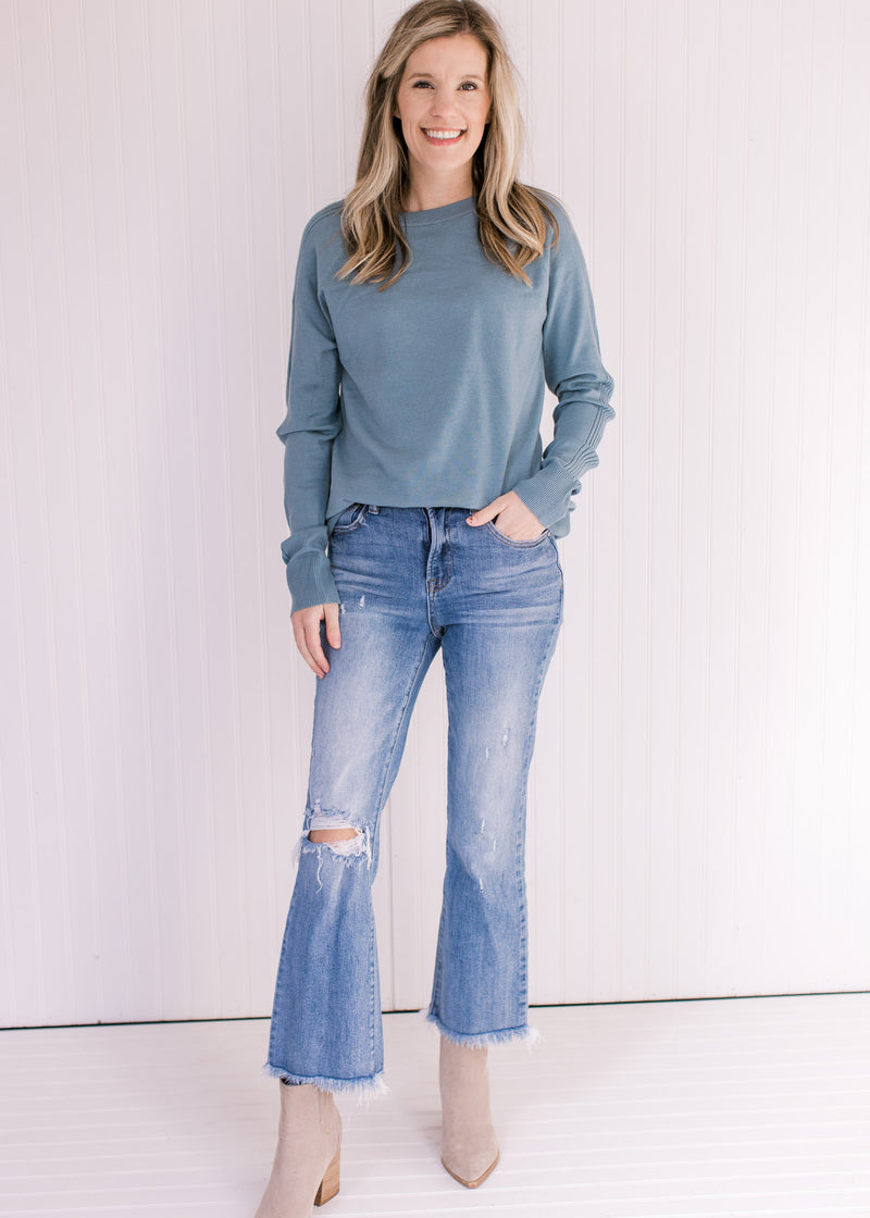 Model wearing jeans and booties with a light blue sweater with a crew neckline and long sleeves.