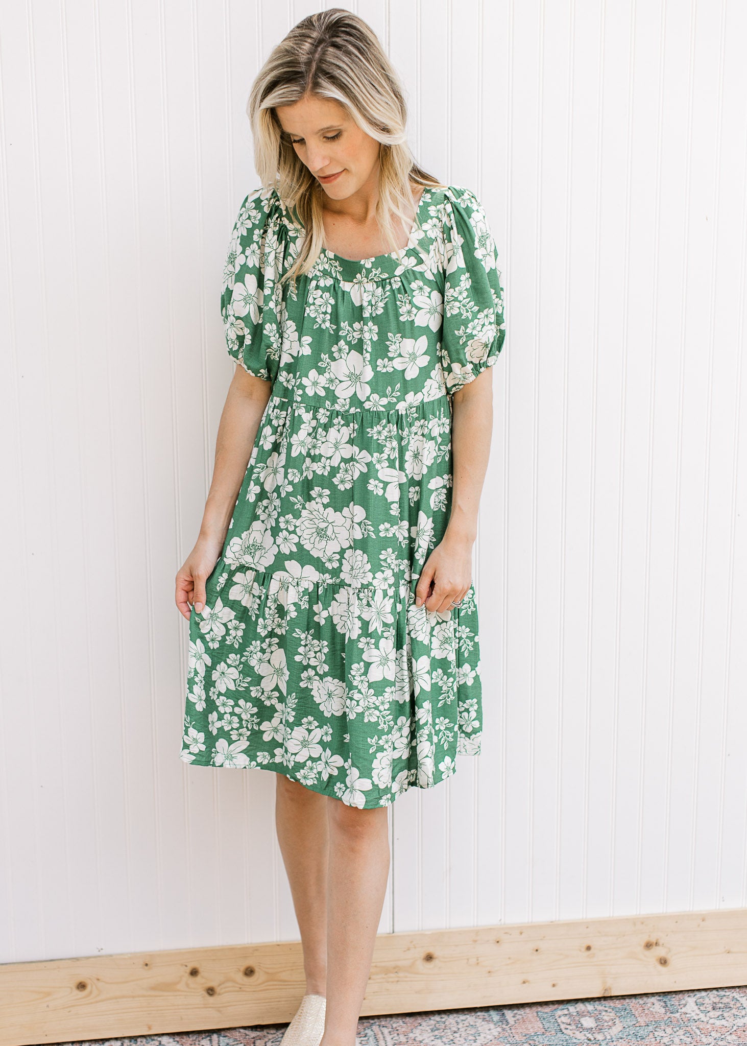 Model wearing a bright green knee length dress with cream floral, square neck and short sleeves.