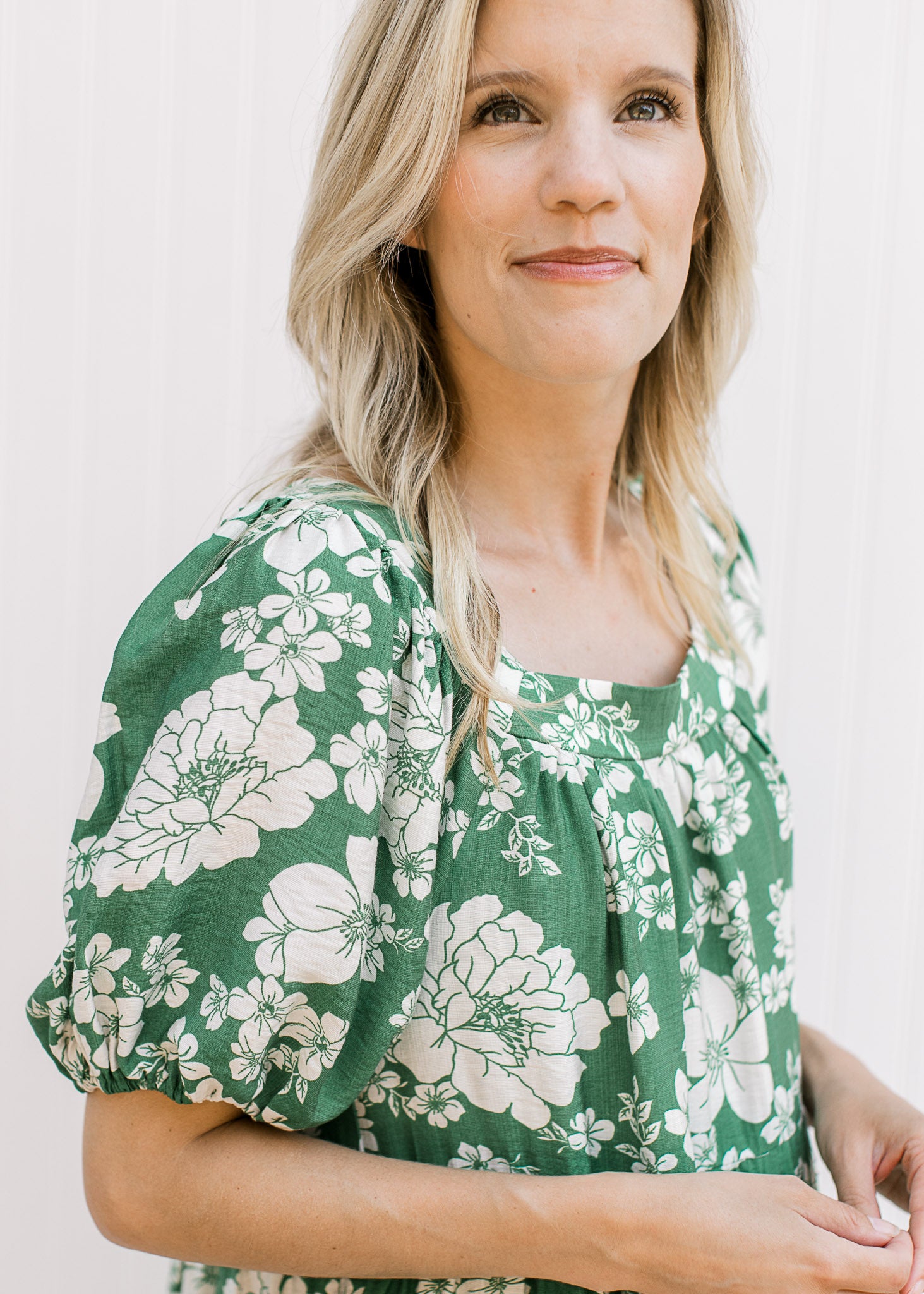 Close up of bubble short sleeves and square neck on a bright green dress with cream floral. 