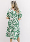 Back view of Model wearing a bright green dress with cream floral, square neck and short sleeves.