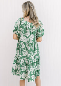 Back view of Model wearing a bright green dress with cream floral, square neck and short sleeves.