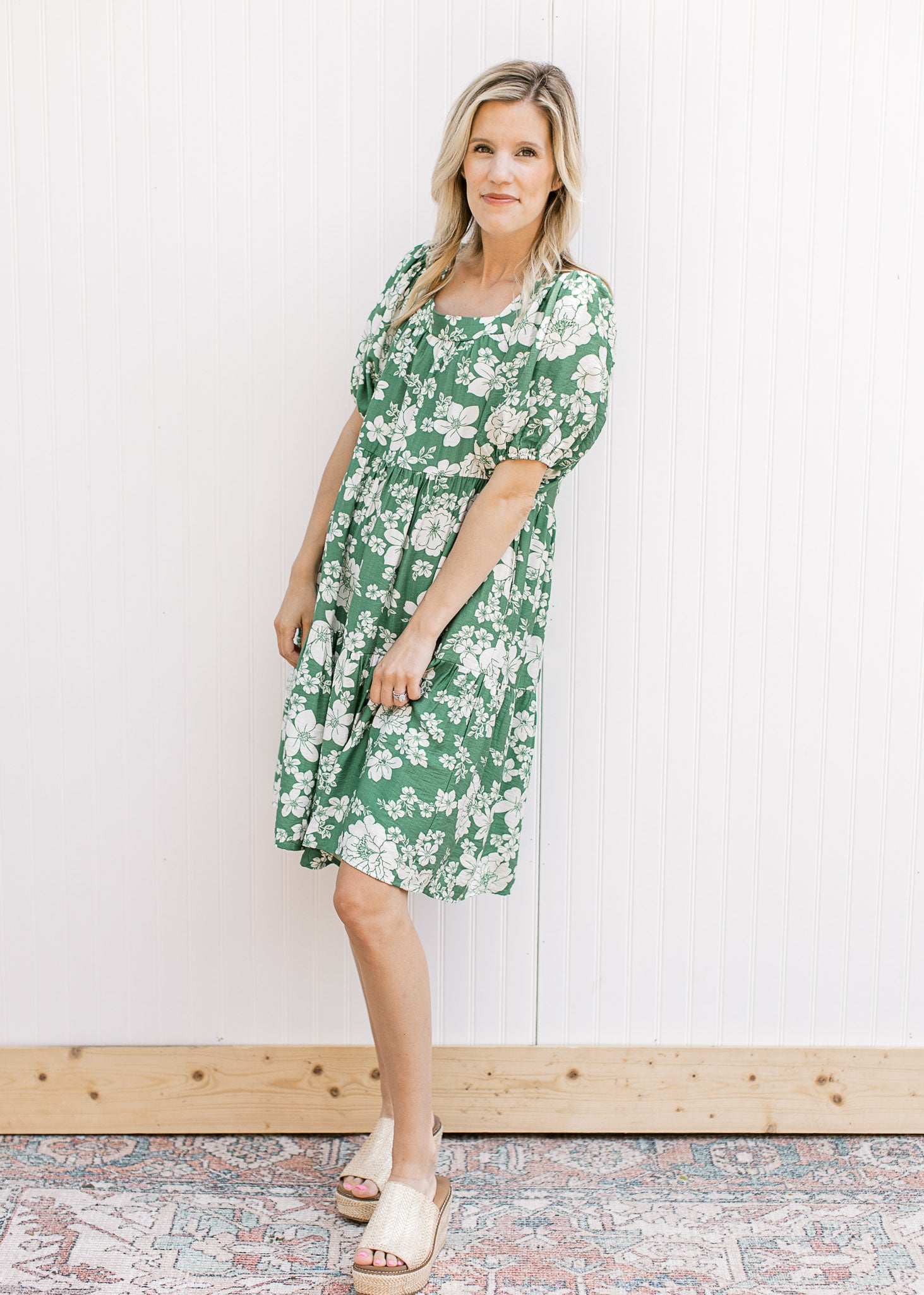 Model wearing a lightweight bright green dress with cream floral, square neck and short sleeves.