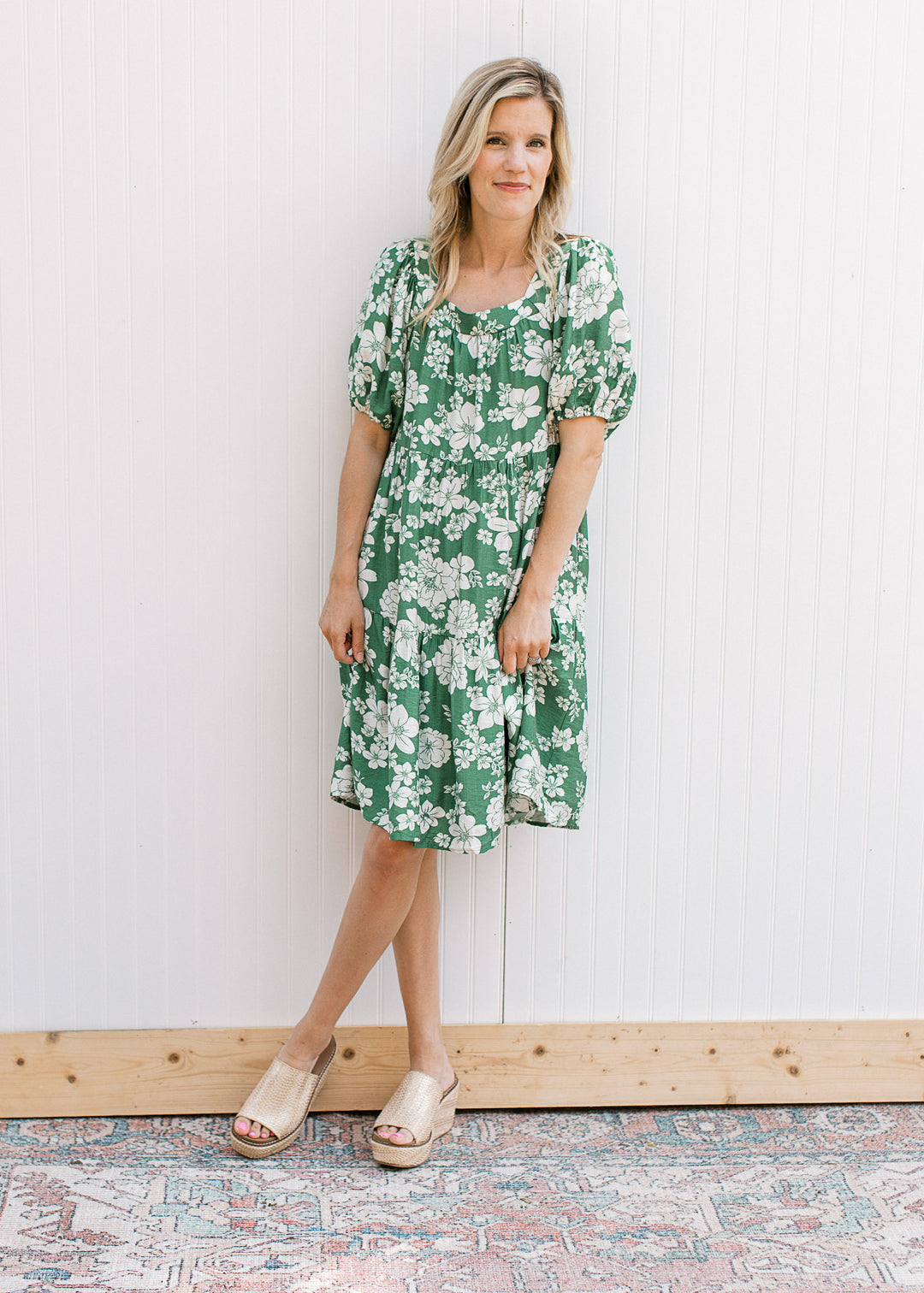 Model wearing wedges and a bright green dress with cream floral, square neck and short sleeves.