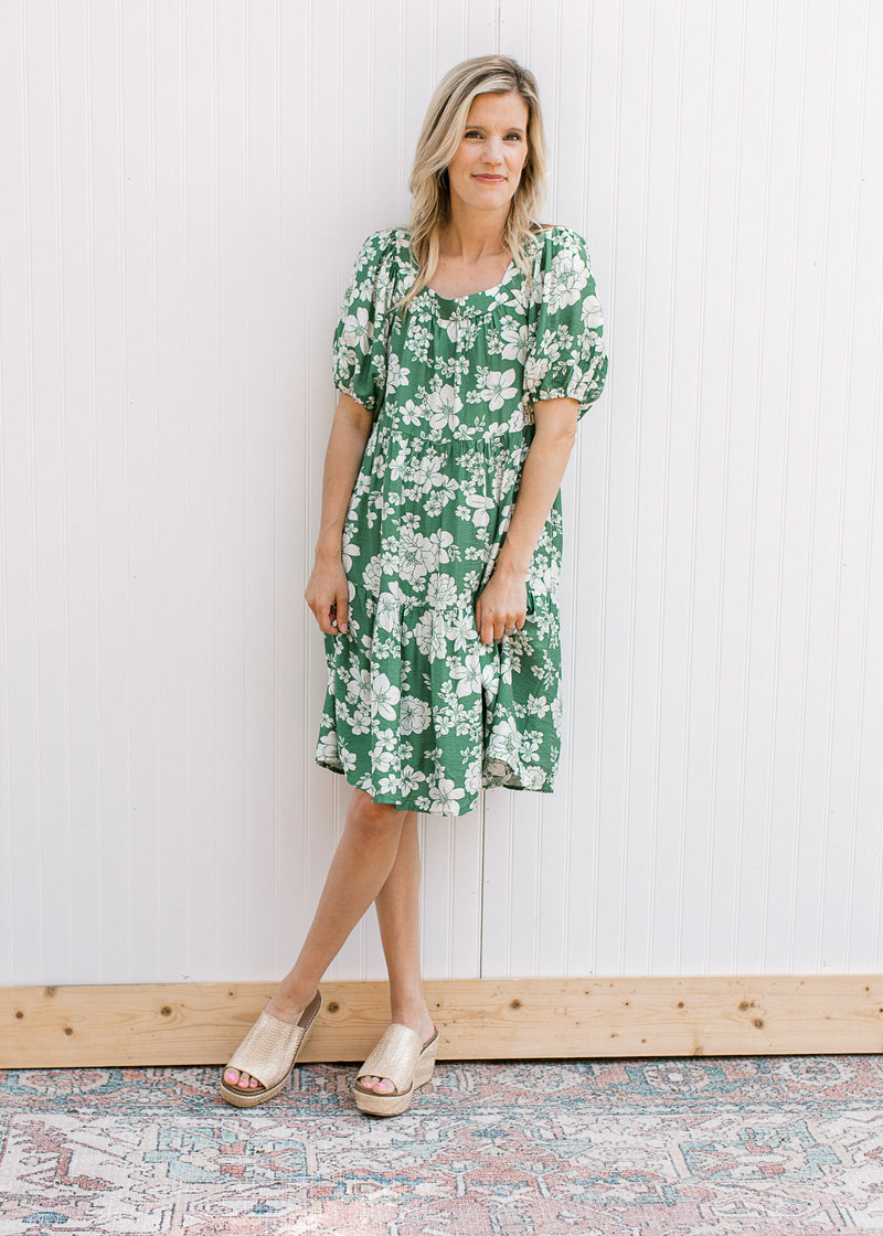 Model wearing wedges and a bright green dress with cream floral, square neck and short sleeves.