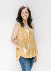 Model wearing a sleeveless mustard yellow v-neck top with a cream floral pattern. 