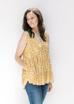 Model wearing a loose fit sleeveless mustard yellow v-neck top with a cream floral pattern. 