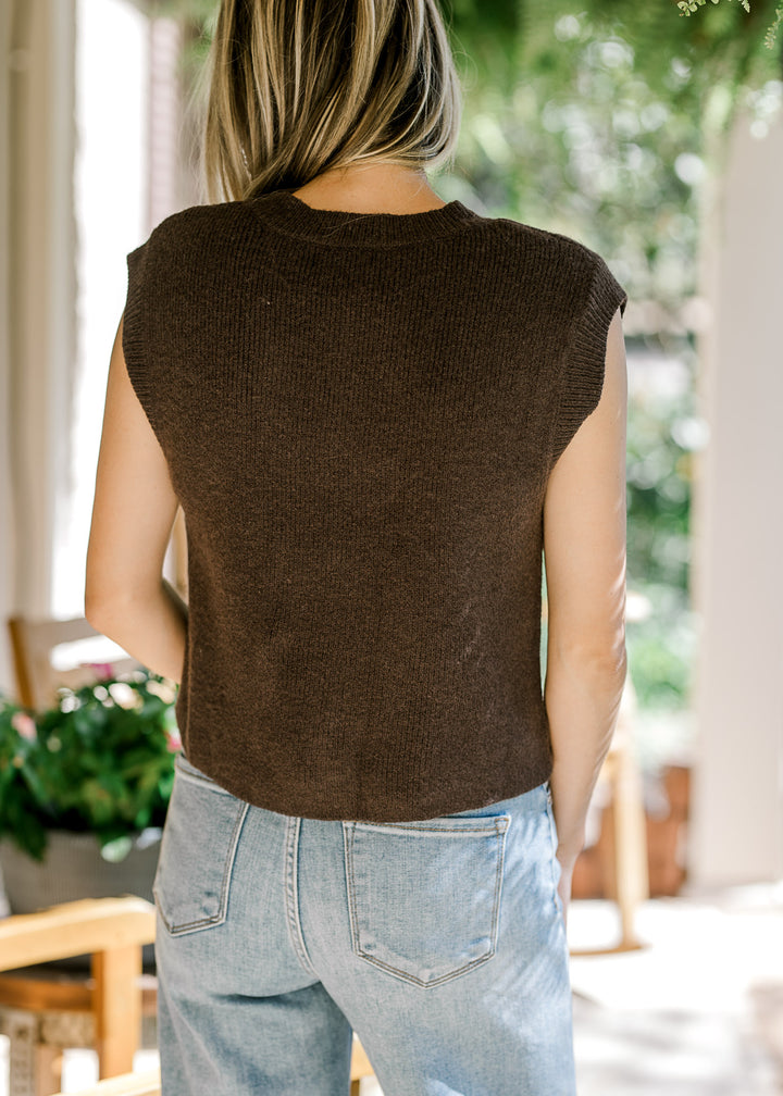 Back view of Model wearing a mocha sleeveless top with patch pockets and gold buttons.  