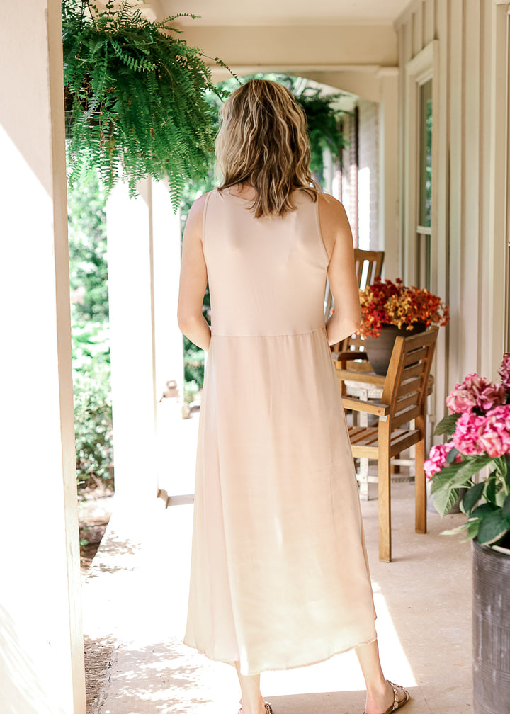 Back view of Model wearing a soft gold maxi with a satin finish, sleeveless design and a round neck.