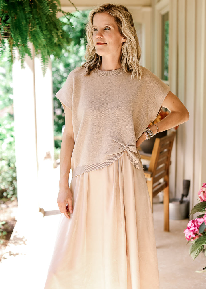 Model wearing a soft gold knit sweater with capped sleeves, round neck and gathered detail at hem.