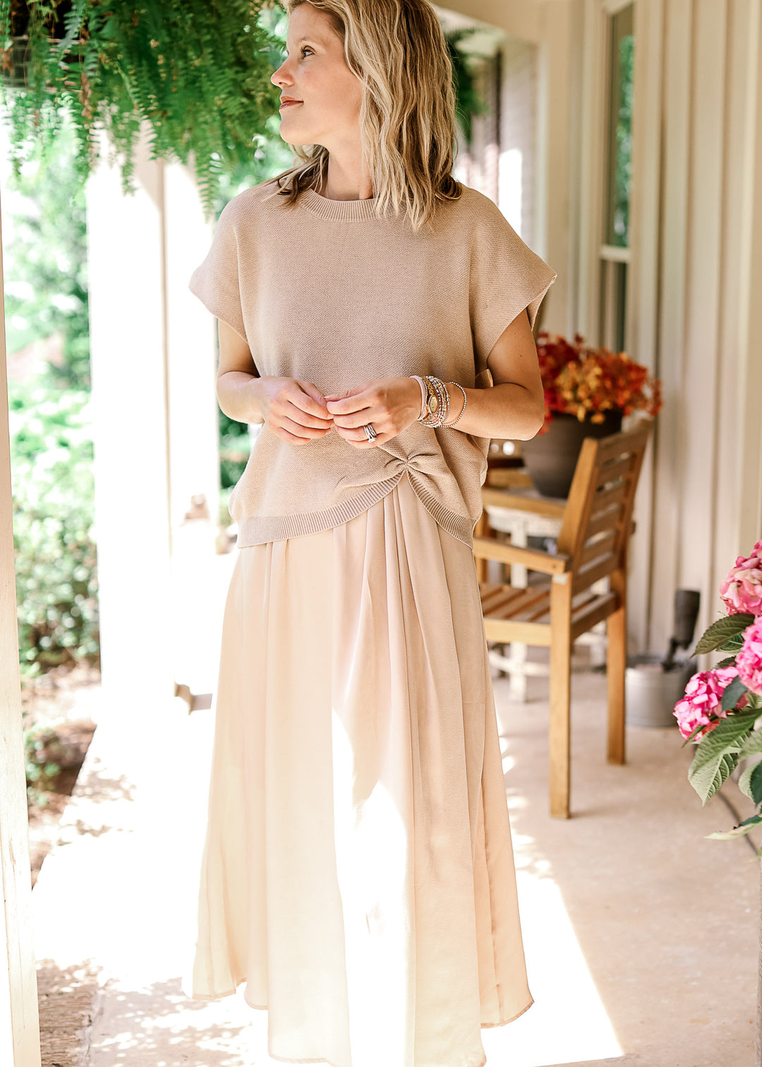 Model wearing a soft gold sweater with capped sleeves, round neck and gathered detail at hem.