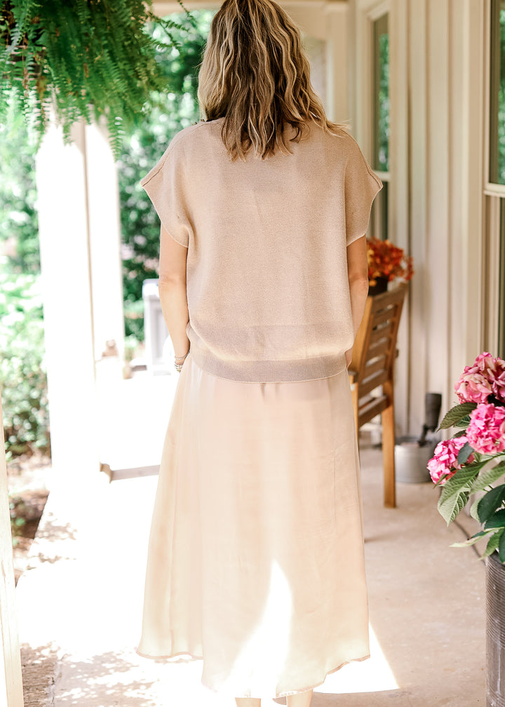 Back view of Model wearing a soft gold knit sweater with capped sleeves and  round neck.