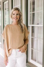 Model wearing a gold textured top with cuffed short sleeve.