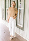 Model wearing white pants and wedges with a gold textured top with cuffed short sleeve.