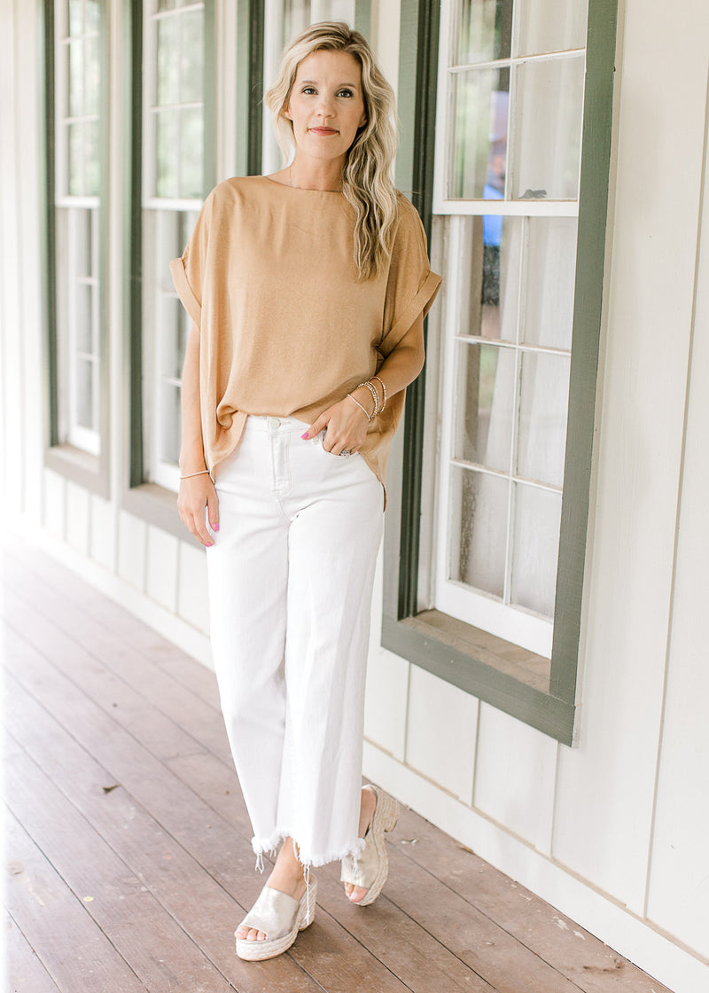 Model wearing white pants and wedges with a gold textured top with cuffed short sleeve.