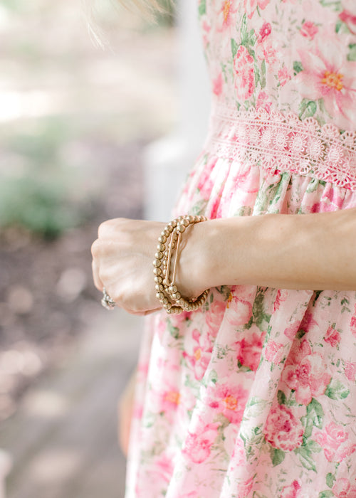 Model wearing 3 bracelets adorned with round golden beads and a thick bar detail. 