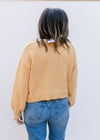 Back view of Model wearing a mustard button up sweater with yellow and green stitched flowers. 