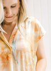 Close up view of Model wearing a golden yellow v-neck top with a watercolor floral design 