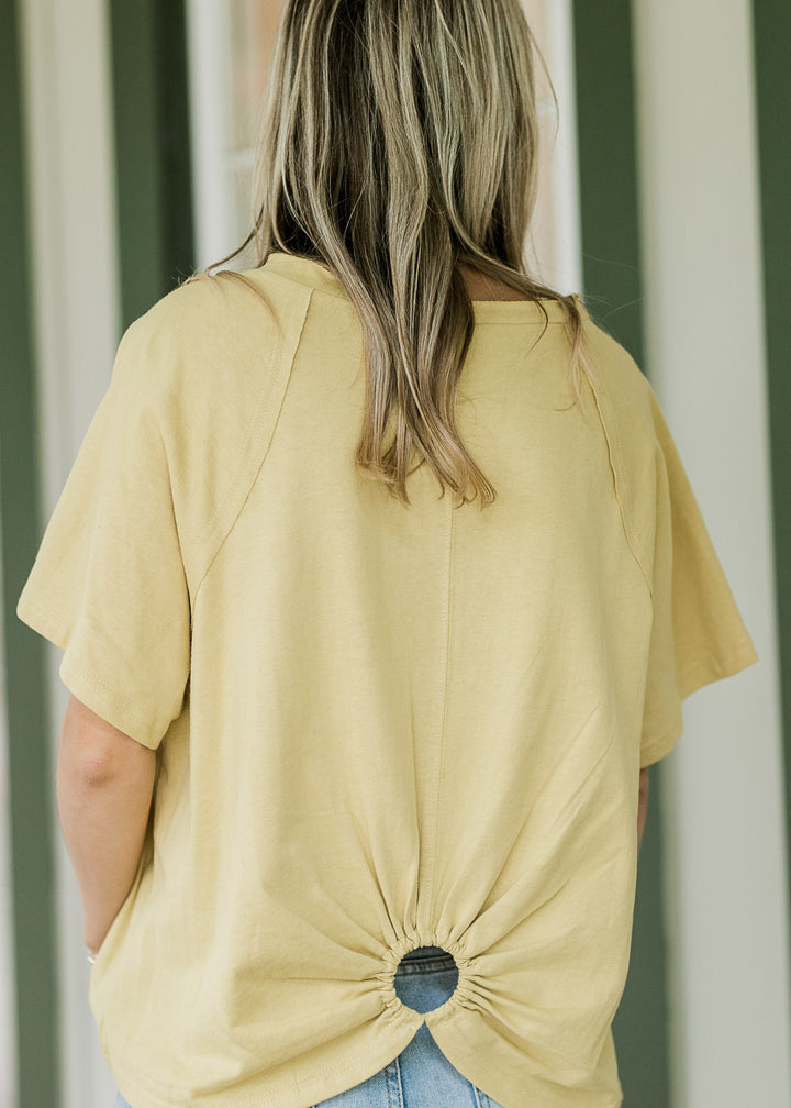Back view of Model wearing a golden yellow tee with short sleeves and a ring with cut out. 