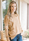 Model wearing a golden sweater with cream heart pattern, long sleeves and classic styling. 