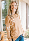 Model wearing a golden sweater with a cream heart pattern long sleeves, and a round neck.