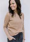 Model wearing jeans with a classic camel colored top with a mocked neckline and long sleeves. 