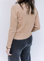 Back view of Model wearing a classic camel colored top with a mocked neckline and long sleeves. 