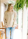 Model wearing a golden shimmer sweater with eyelets on the long sleeves and a round neck. 