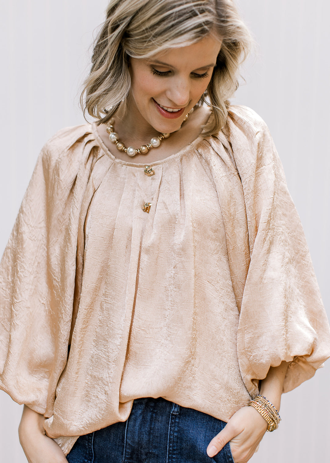 Front detail of Golden Shimmer Top with neckline pleats, elbow-length bubble sleeves and two decorative gold buttons.