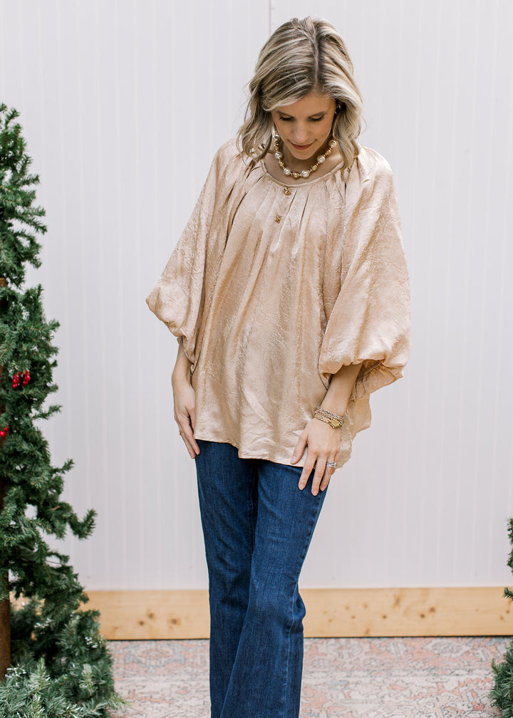 Model wearing Golden Shimmer Top untucked with dark jeans, showing flowy silhouette and elbow-length bubble sleeves.
