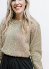 Model wearing a gold sweater with a tinsel material, round neck and long sleeves. 