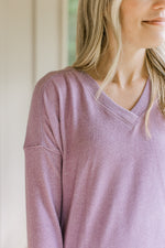 Close up of ribbed v-neck and extended shoulder on a lavender long sleeve sweater. 