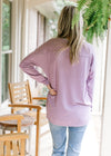 Back view of Model wearing a lavender sweater with  a ribbed v-neck and long sleeves. 