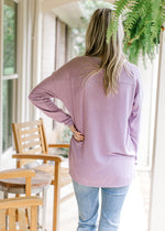 Back view of Model wearing a lavender sweater with  a ribbed v-neck and long sleeves. 