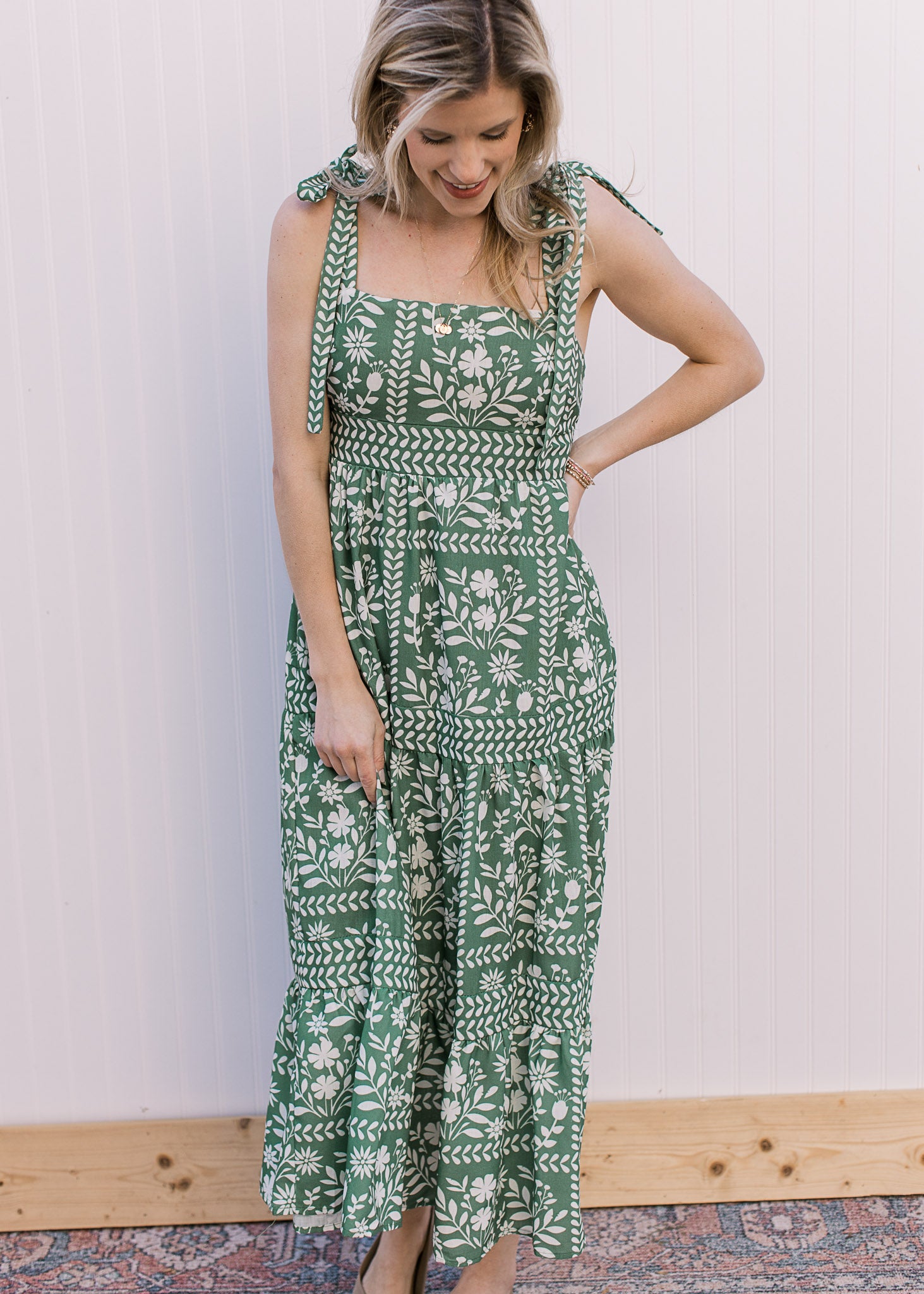 Model wearing a green maxi with cream floral, tie spaghetti straps and a square neckline. 