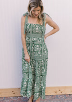 Model wearing a green maxi with cream floral, tie spaghetti straps and a square neckline. 