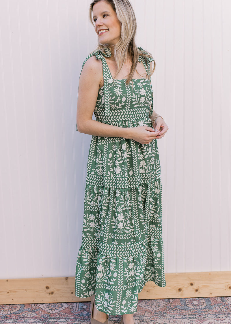 Model wearing flats and a green maxi with cream floral, tie spaghetti straps and a square neckline. 