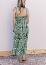 Back view of Model wearing a green maxi with cream floral, tie spaghetti straps and a square neck. 