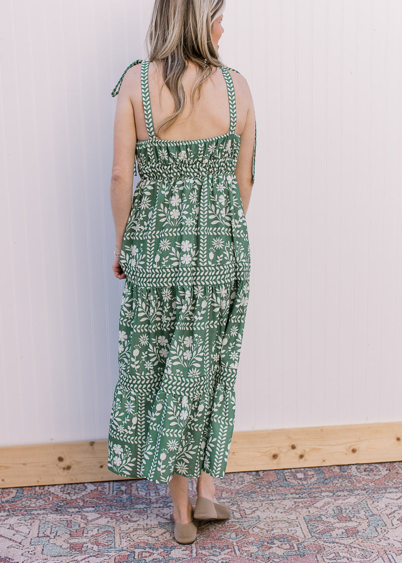 Back view of Model wearing a green maxi with cream floral, tie spaghetti straps and a square neck. 