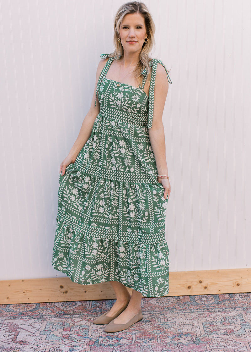 Model wearing a polyester green maxi with cream floral, tie spaghetti straps and a square neck. 