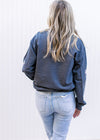 Back view of Model wearing a charcoal sweatshirt with 3 nutcrackers, pink text and long sleeves. 