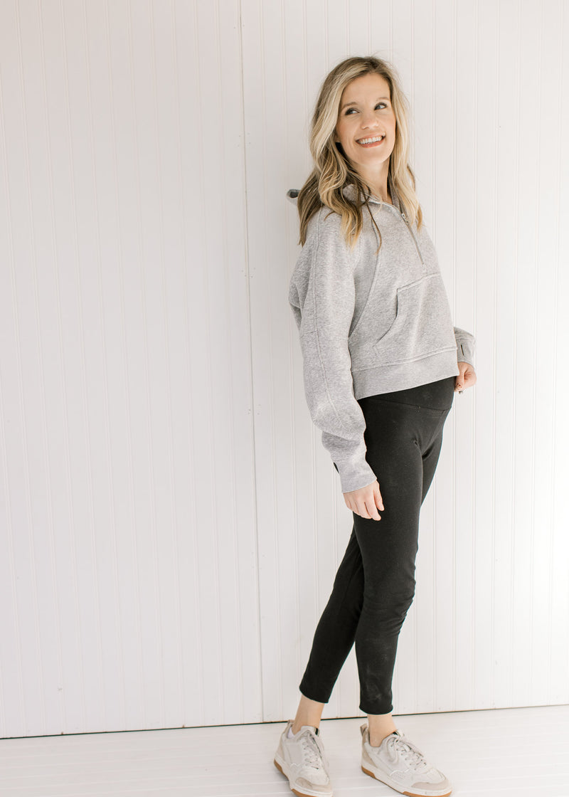 Model wearing workout pants and sneakers with a gray pullover with a 1/4 zip and long sleeves.