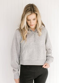 Model wearing an gray pullover with a 1/4 zip, long sleeves and a front pouch pocket.