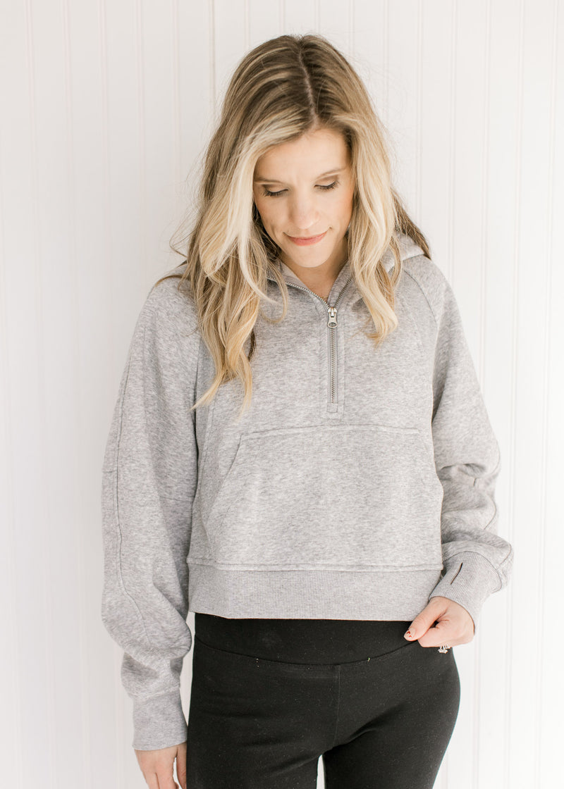 Model wearing an gray pullover with a 1/4 zip, long sleeves and a front pouch pocket.