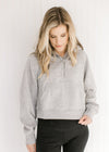 Model wearing an gray pullover with a 1/4 zip, long sleeves and a front pouch pocket.